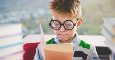 Close-up of schoolkid reading book in classroom